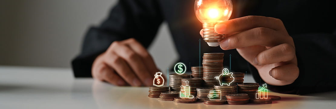 Businesswoman hand holding glowing lightbulb on coin stacking